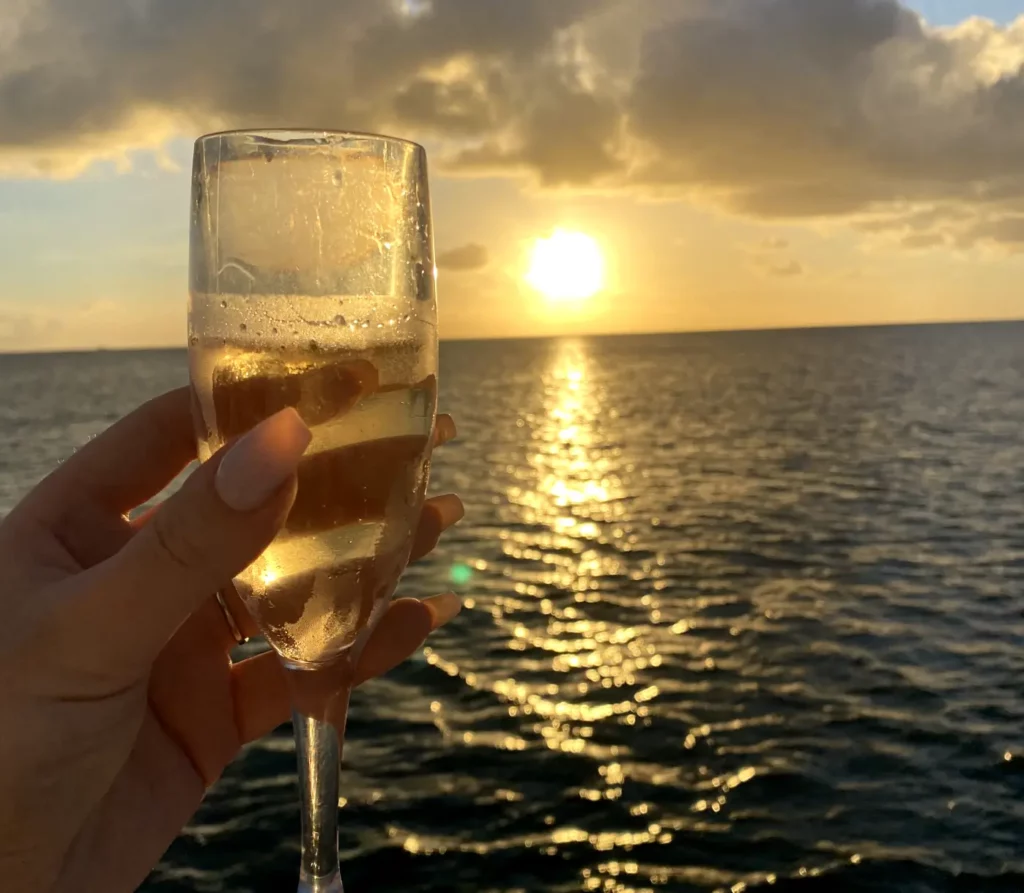 A glass of champagne held up against a stunning sunset view from a sailboat in Saint Lucia