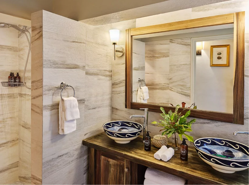 Charming beachfront cottage bathroom at East Winds Resort, St. Lucia, with natural stone finishes and wooden vanity, all inclusive