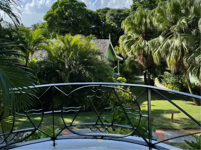 Scenic resort grounds framed by palm trees and classic iron railing |East Winds Luxury Resort Saint Lucia
