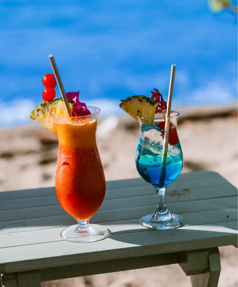 Two tropical cocktails served on the beach, symbolizing relaxation and indulgence at East Winds Resort
