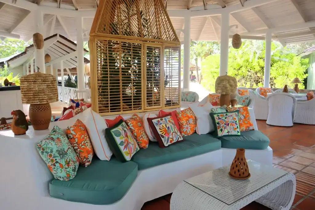 A beautifully designed open-air lounge at East Winds Resort, St. Lucia, featuring cozy seating with vibrant tropical pillows, elegant natural décor, and lush greenery creating a serene and inviting ambiance.