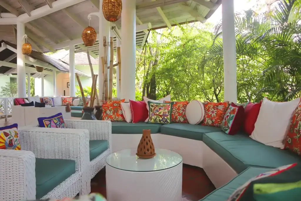Beautifully designed open-air lounge at East Winds Resort, St. Lucia, featuring comfortable seating with vibrant tropical pillows, elegant natural decor, and lush greenery creating a serene and inviting ambiance.