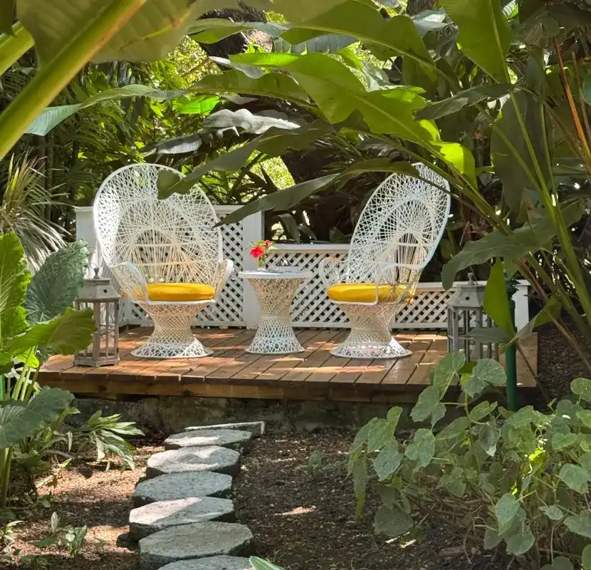 Garden seating area with white wicker chairs and tropical greenery | East Winds Luxury Resort Saint Lucia